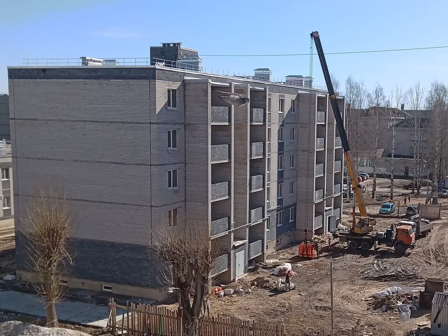 Grue mobile déposant des matériaux sur la toiture d'un immeuble